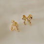 Gold simple bow clip on stud earrings displayed at angle on white background showing detailed design and shine