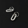 Silver spiral clip-on dangle hoop earrings displayed on black background, showcasing textured twisted design and polished metallic finish from above.