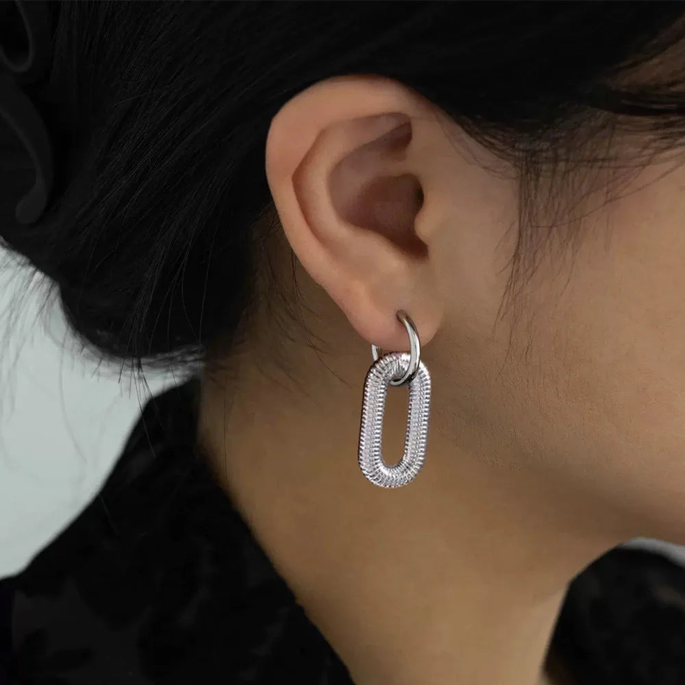 Silver spiral clip-on dangle hoop earrings side view worn on ear, textured finish