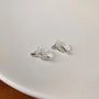Silvery snake invisible clip-on stud earrings displayed on white surface, showing polished silver finish and curved design detail
