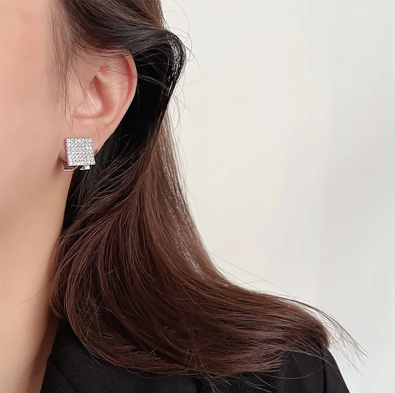 Silver square pavé clip-on stud earrings side view worn on model with dark hair against white background