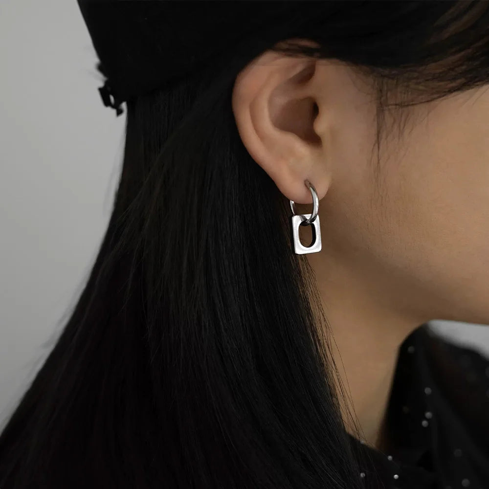 Modern minimalist square clip-on earrings in silver, side view worn on ear with long dark hair