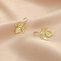 Gold sterling silver maple leaf clip earrings displayed on beige fabric, front view showing detailed leaf design
