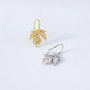 Sterling silver maple leaf cuff earrings in white and yellow gold shown at angle on white background