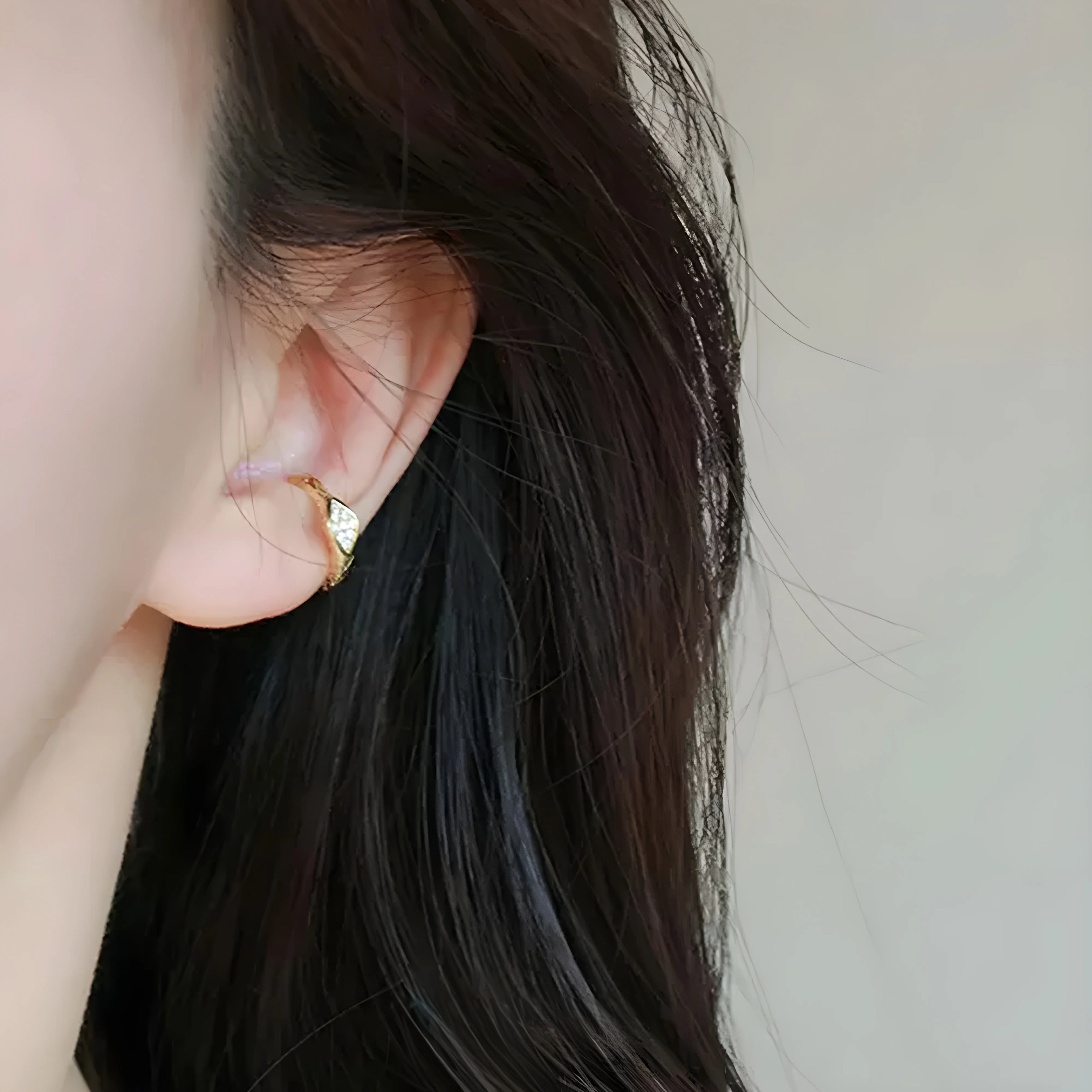 Gold sterling silver Ouroboros ear cuff side view worn on ear with long dark hair