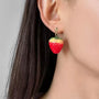 Red strawberry charm clip-on earrings with gold details, side view on model with dark hair