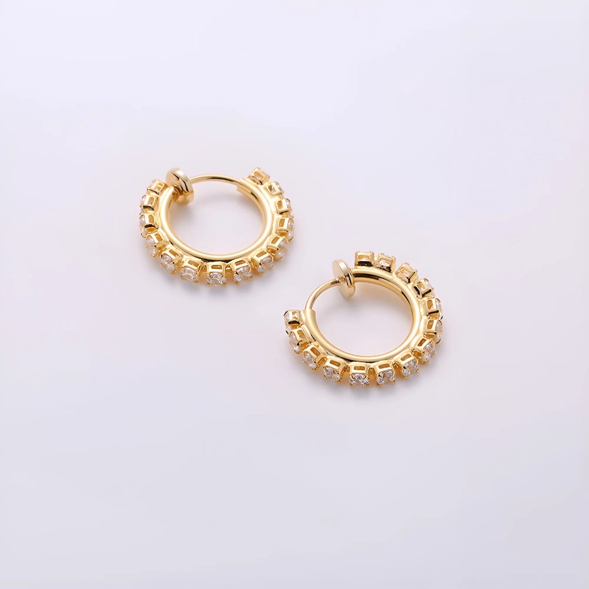 Small gold mini hoop earrings with a sliding spring-hoop clip-on mechanism, perfect for all-day wear.