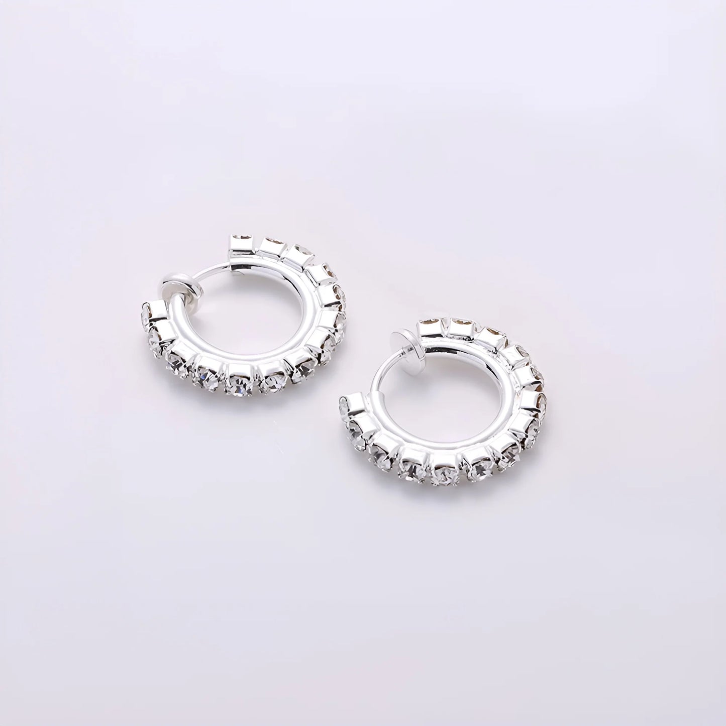 Small silver mini hoop earrings with a sliding spring-hoop clip-on mechanism, perfect for daily wear.