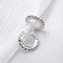 Silver diamond clip-on hoop earrings displayed at angle on white textured background