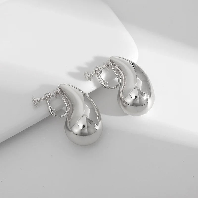 Silver teardrop clip-on earrings displayed at angle on white background showing polished finish and closure detail