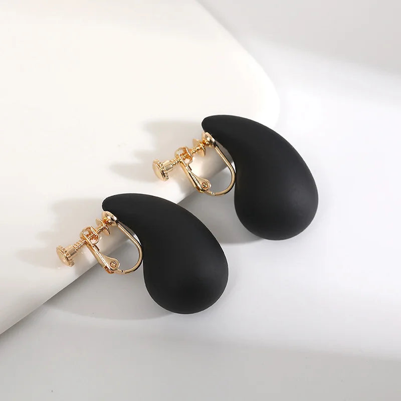 Black teardrop clip-on earrings with gold hardware displayed on white background, front angle view