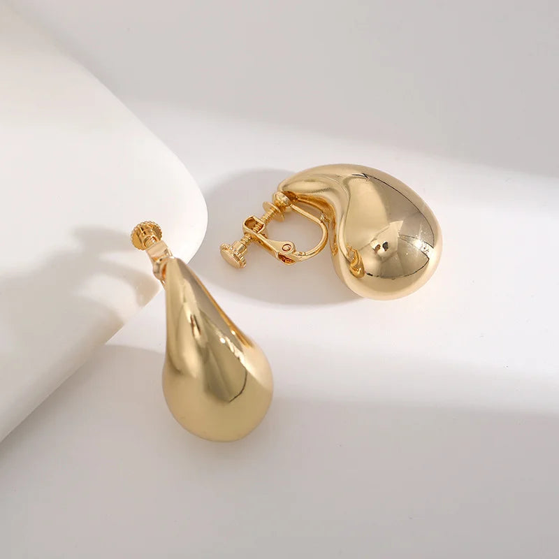 Gold teardrop clip-on earrings displayed at angle on white background showing polished finish and closure detail