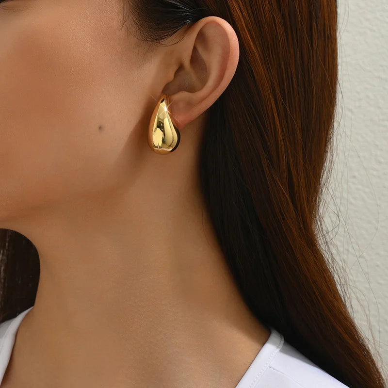 Gold teardrop clip-on earrings side view worn on ear, polished finish, elegant design