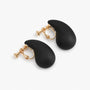 Black teardrop clip-on earrings with gold hardware displayed on white background, side angle view