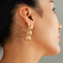 Gold textured shell clip-on earrings side view worn on ear, showcasing three dangling shell-shaped pendants in polished gold finish