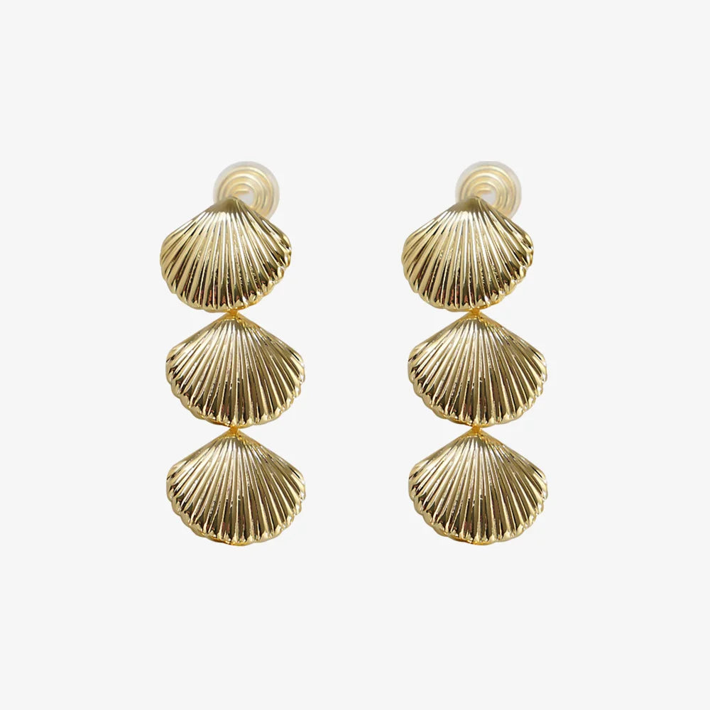 Vue de face des boucles d'oreilles à clip en forme de coquillage texturé, couleur or, mettant en valeur la texture complexe inspirée des coquillages.
