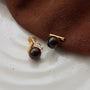 Tiger's Eye clip on earrings with gold accents displayed on white marble surface with brown fabric