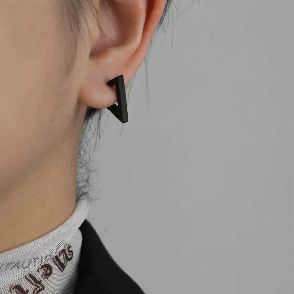 Black geometric triangle clip-on earrings side view worn on ear against white background