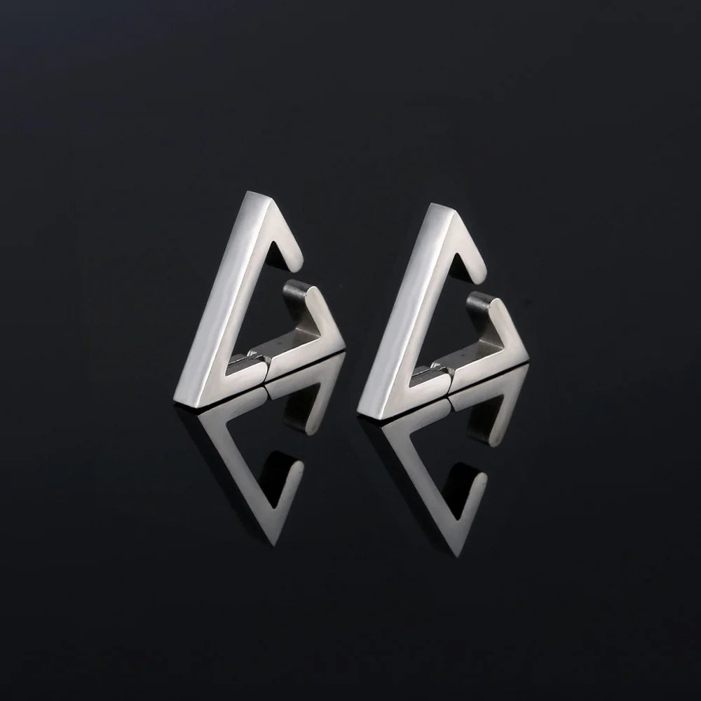 Pair of silver geometric triangle clip-on earrings with modern angular design, displayed at three-quarter view on dark background