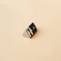 Triangle magnetic stud earrings in black displayed at an angle on a beige background showing the metallic and matte finish details