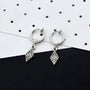 Silver vintage tribal drop clip-on earrings with ornate diamond charms, displayed on polka dot background