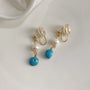 Turquoise clip on pearl earrings with gold hardware and clear silicone backing displayed on white surface