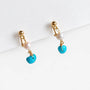 Turquoise clip on pearl earrings with gold accents clipping white paper