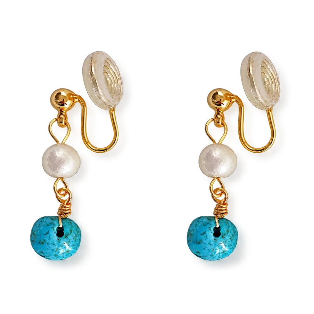 A pair of gold-tone clip-on dangle earrings featuring a white pearl bead, a round turquoise blue stone disc, and a textured clear resin back, shown on a plain white background.