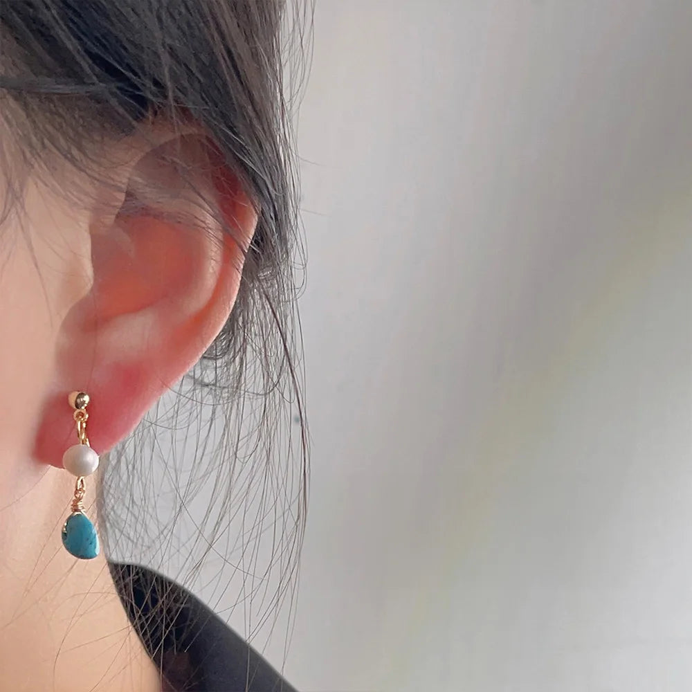 Turquoise clip on pearl earrings side view worn on ear with gold accents