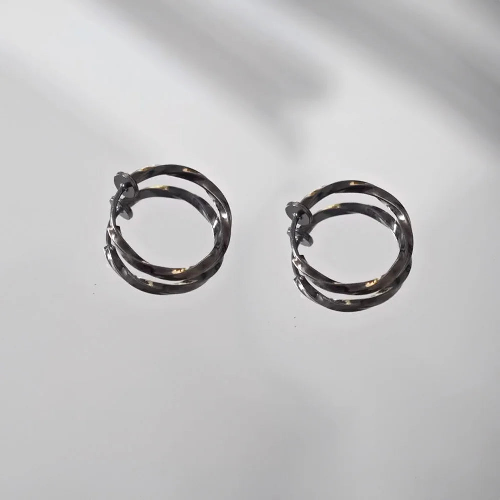Twisted huggie clip on hoop earrings in black, front view on white background