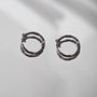 Twisted huggie clip on hoop earrings in black, front view on white background