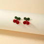 Velvet cherry clip-on earrings with green leaves displayed on white background, front view