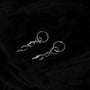 Silver thorn vine clip-on hoop earrings displayed at angle on black background