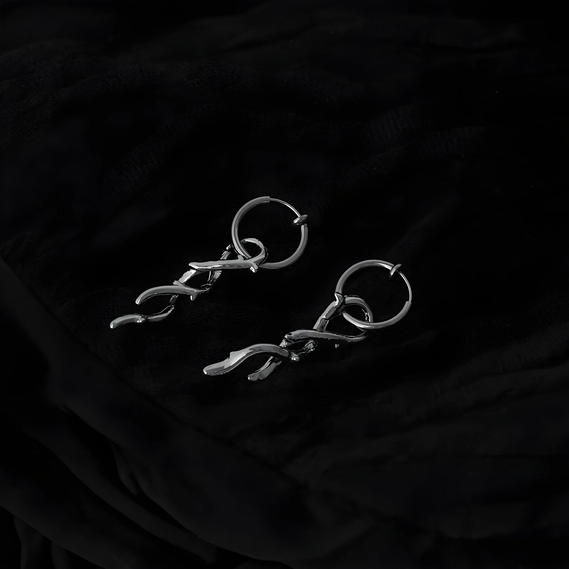 Silver thorn vine clip-on hoop earrings displayed at angle on black background