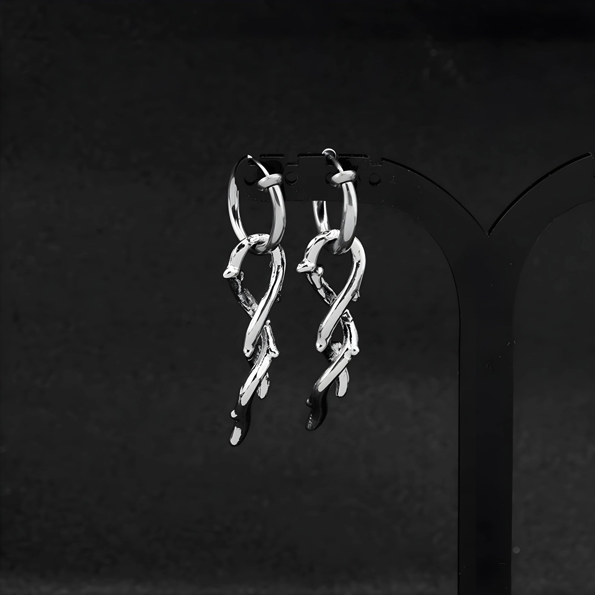Silver thorn vine clip-on hoop earrings front view on black display stand
