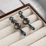 Vintage multi-gem drop clip-on earrings with smoky gray and blue stones in gunmetal finish, displayed in jewelry box