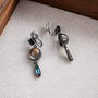 Vintage multi-gem drop clip-on earrings with smoky quartz and blue topaz stones on beige fabric background