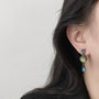 Vintage multi-gem drop clip-on earrings side view on model with dark hair, silver-toned metal design