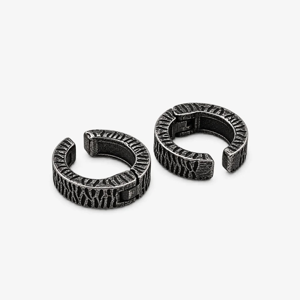 A pair of textured black metal huggie hoop earrings with a hammered finish.
