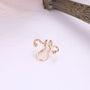 Gold wavy tragus cuff displayed at angle on white background with wooden branch detail