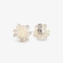 White flower clip on earrings displayed on brown leather pad with silver hardware detail visible