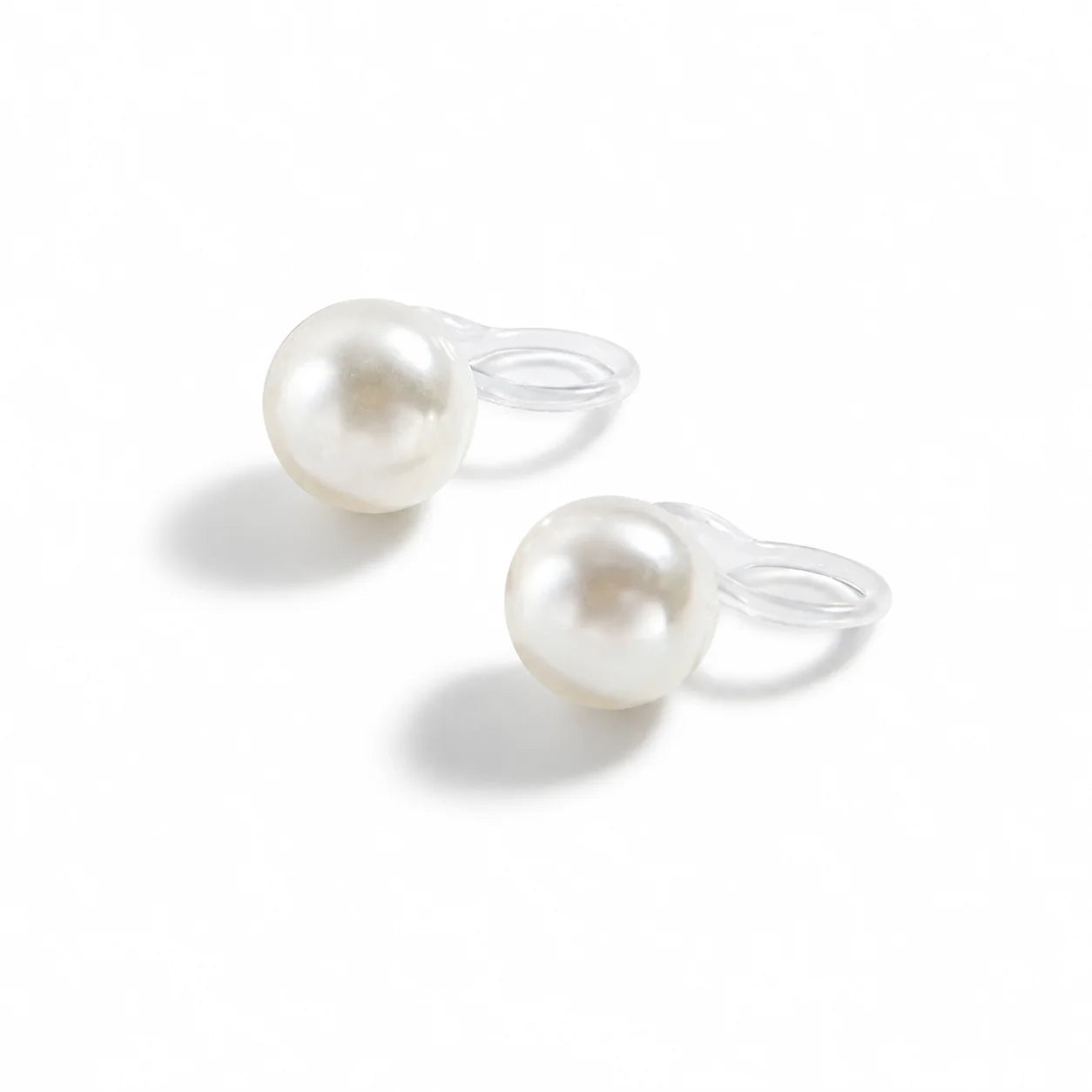 A pair of white pearl stud earrings with clear silicone loops, shown on a clean white background with soft shadows.