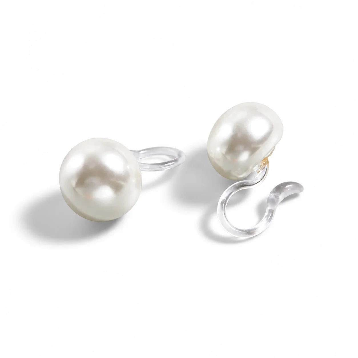 A pair of white pearl earrings with clip, shown on a clean white background.
