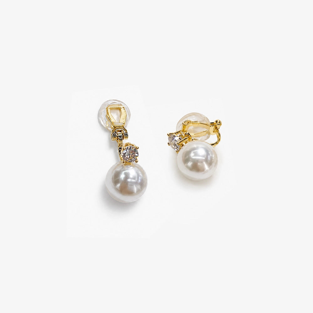 White pearl drop clip on earrings in gold displayed with gold hardware and rhinestone accents