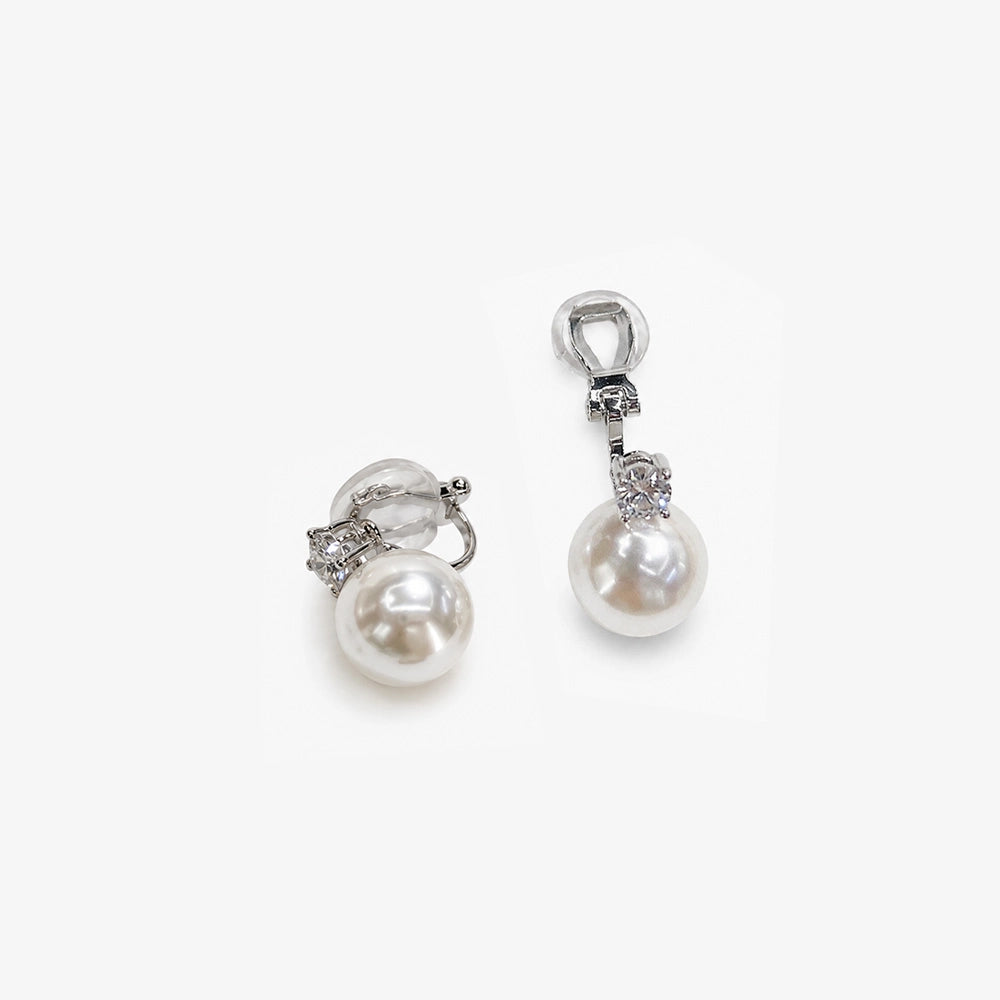 White pearl drop clip on earrings in silver, top view on white background displaying lustrous pearls and rhinestone accents