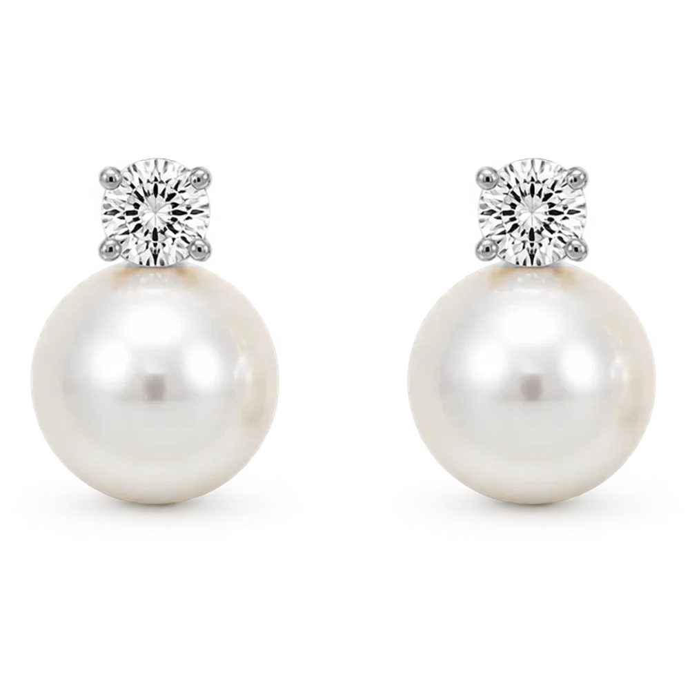 A pair of silver-toned drop earrings featuring a large white pearl and a round clear gemstone, shown on a white background.