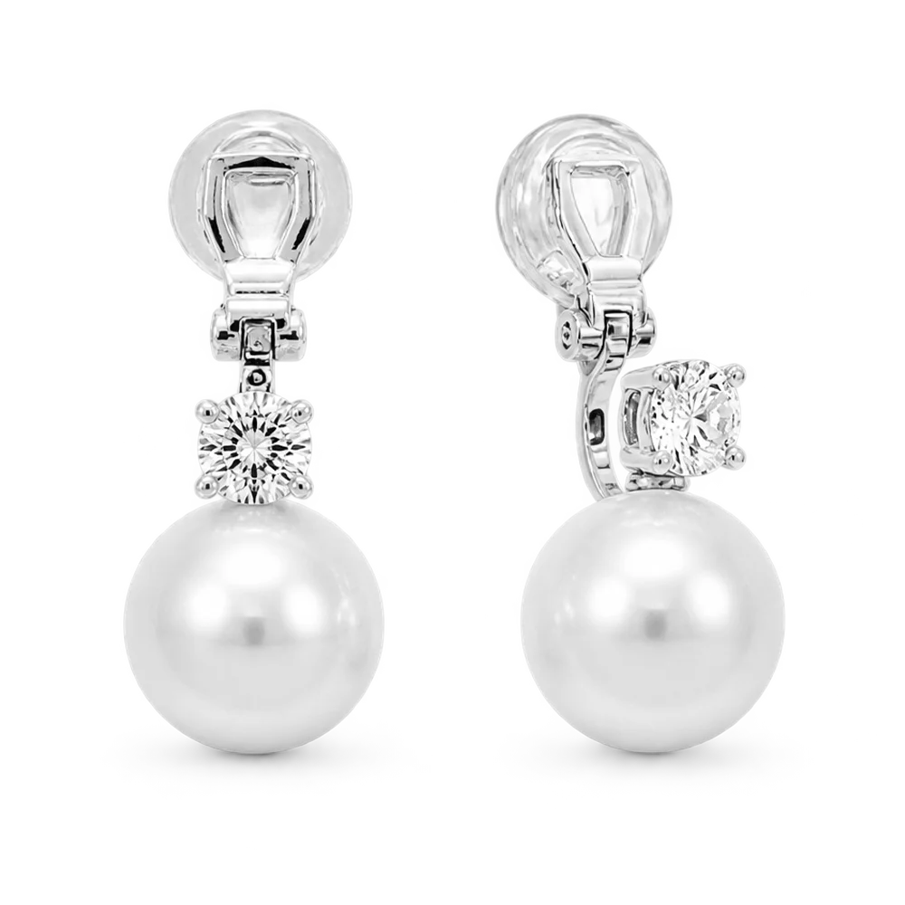 A pair of silver-toned drop earrings featuring a large white pearl and a round clear gemstone, shown on a white background.