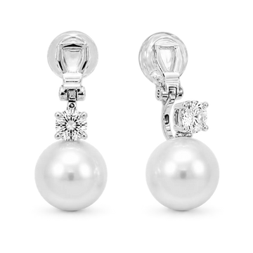 A pair of silver-toned drop earrings featuring a large white pearl and a round clear gemstone, shown on a white background.
