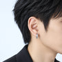 A close-up of a person's ear wearing a small silver earring with a white zircon design.