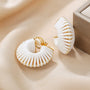 White leather wrapped clip-on hoop earrings displayed on beige fabric, showcasing gold accents and textured design detail